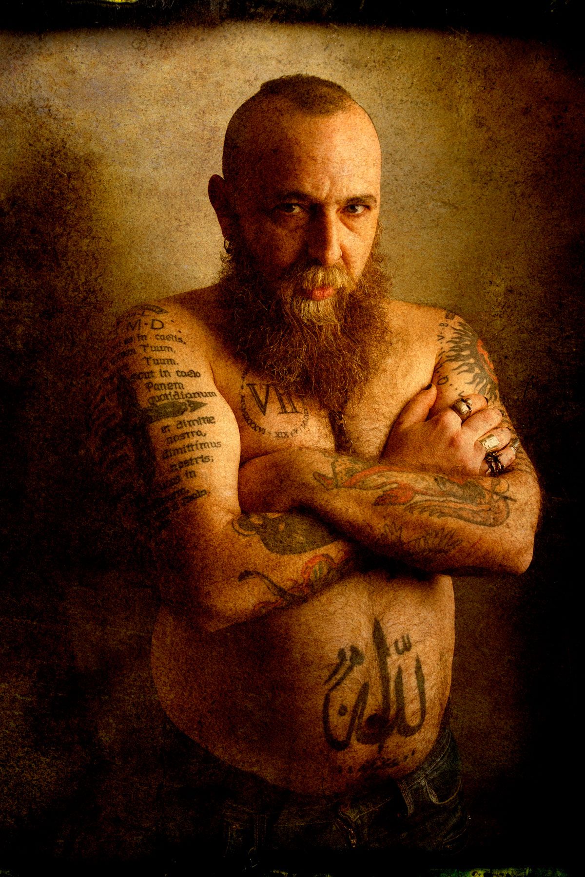 The Normand — tattooed man with arms crossed, warm tones
